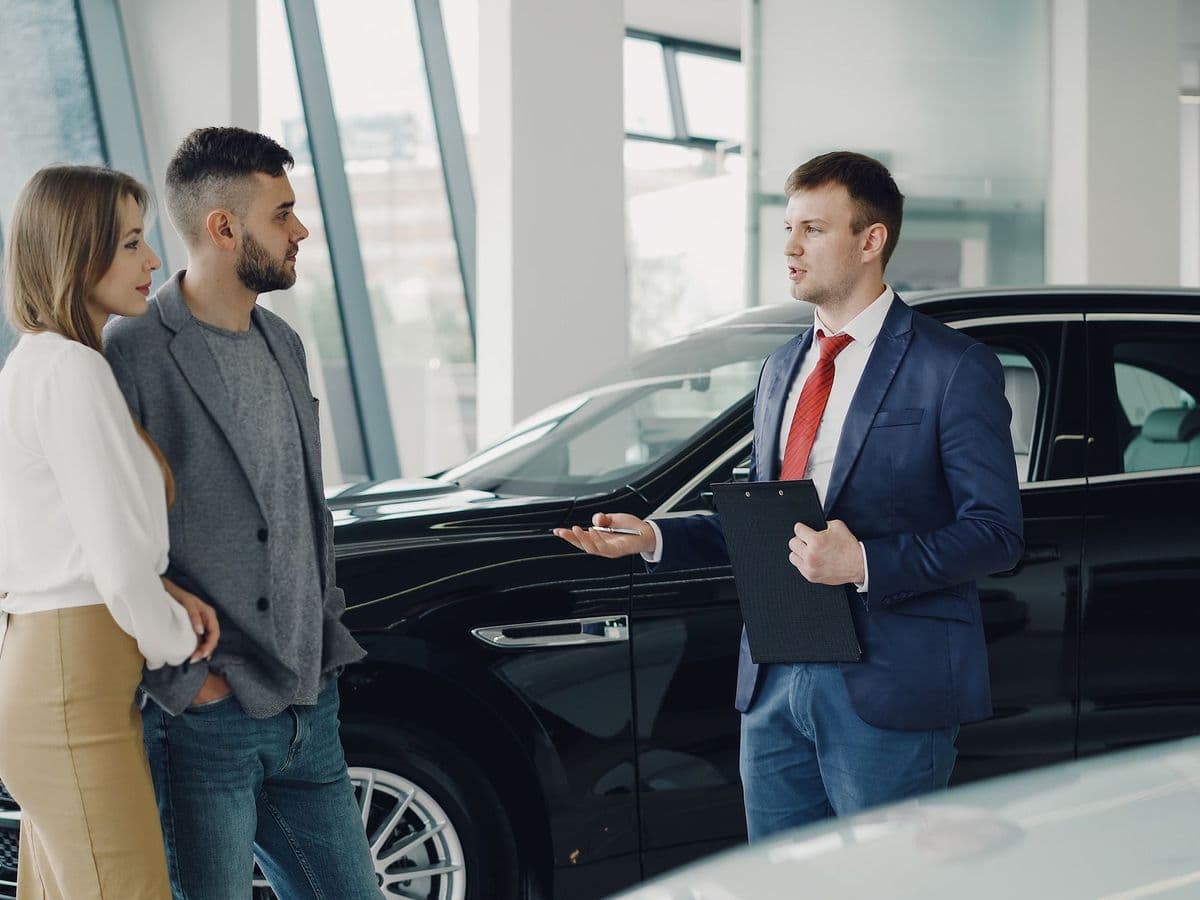 Vendedor apresentando o carro para um casal no showroom